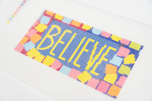 Close angled view of the yellow believe lettering and the pink, orange, yellow and light blue sticky note squares
