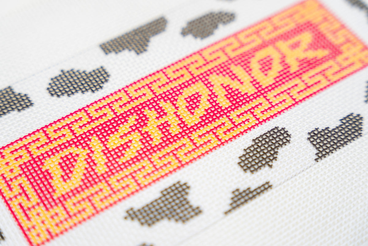 Close-up of the Dishonor on Your Cow printed canvas showing the gold lettering, fretwork border and cow print on the 13 mesh grid