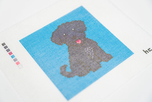 Close angled view of the black schnoodle's curly face, pink tongue and gray chest on the turquoise 18 mesh canvas