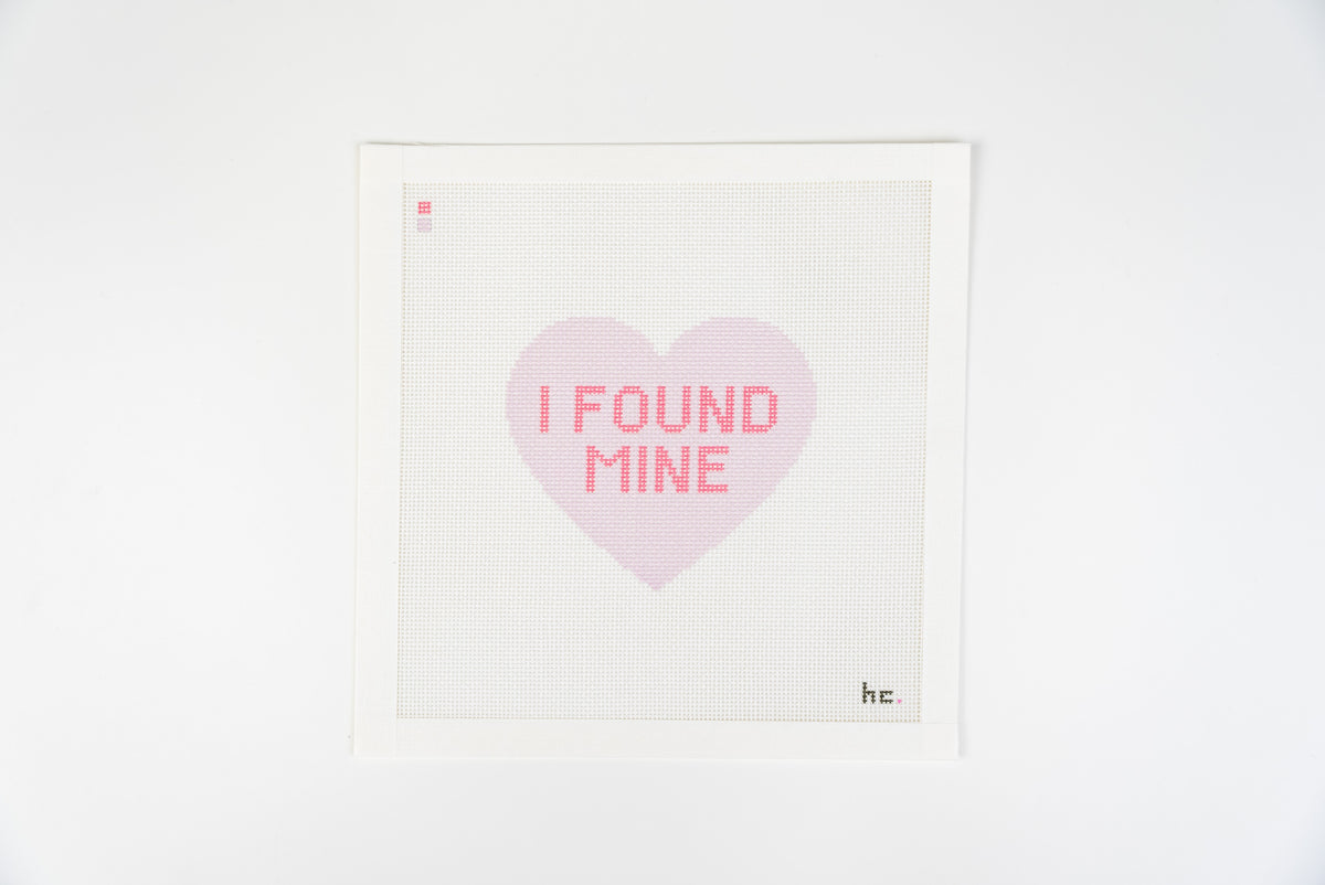 Printed needlepoint canvas of a lilac candy heart reading I found mine in hot pink letters on a white background, full view