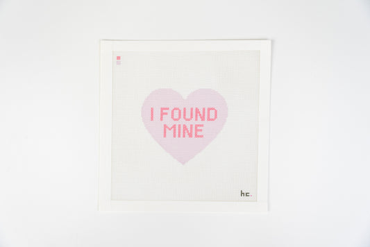 Printed needlepoint canvas of a lilac candy heart reading I found mine in hot pink letters on a white background, full view