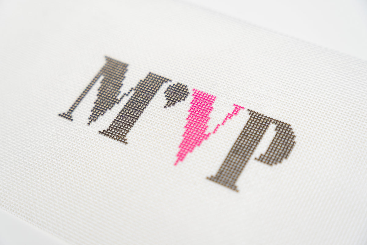 Close angled view of the charcoal M and P with the hot pink V on 13 mesh canvas