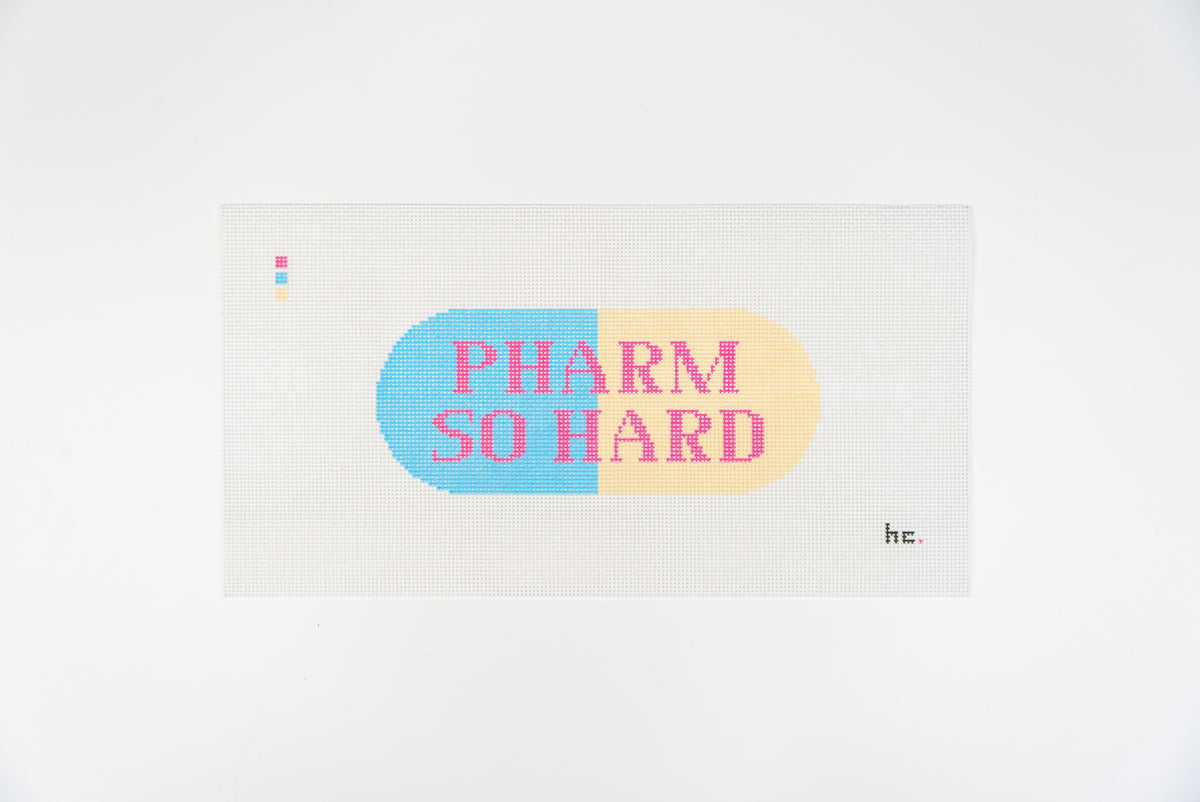 Printed needlepoint canvas of a sky blue and pale yellow capsule reading pharm so hard in hot pink letters, full view