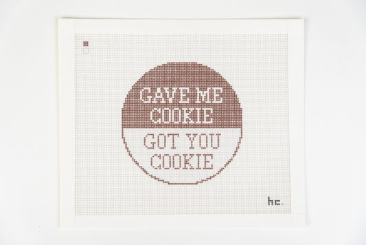 Printed needlepoint canvas with a round design, brown top half reading gave me cookie and white half reading got you cookie, 18 mesh, full view