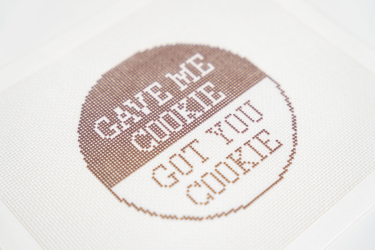 Printed needlepoint canvas, close angled view of the brown and white lettering on 18 mesh