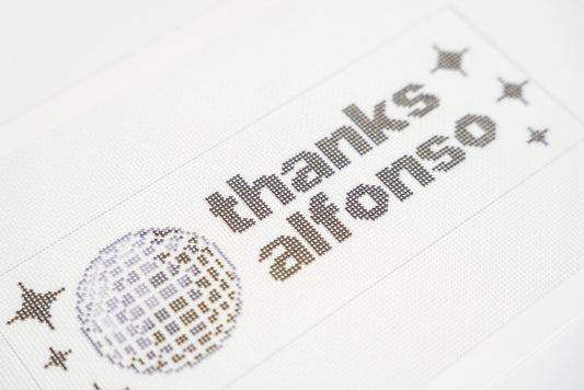 Printed needlepoint canvas reading thanks alfonso, close angled view of the letters and disco ball on 18 mesh