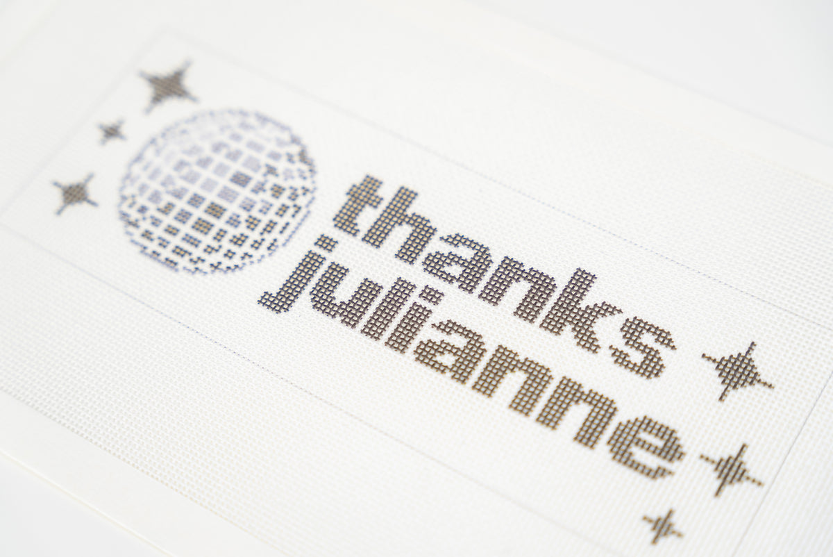 Printed needlepoint canvas reading thanks julianne, close angled view of the letters and disco ball on 18 mesh